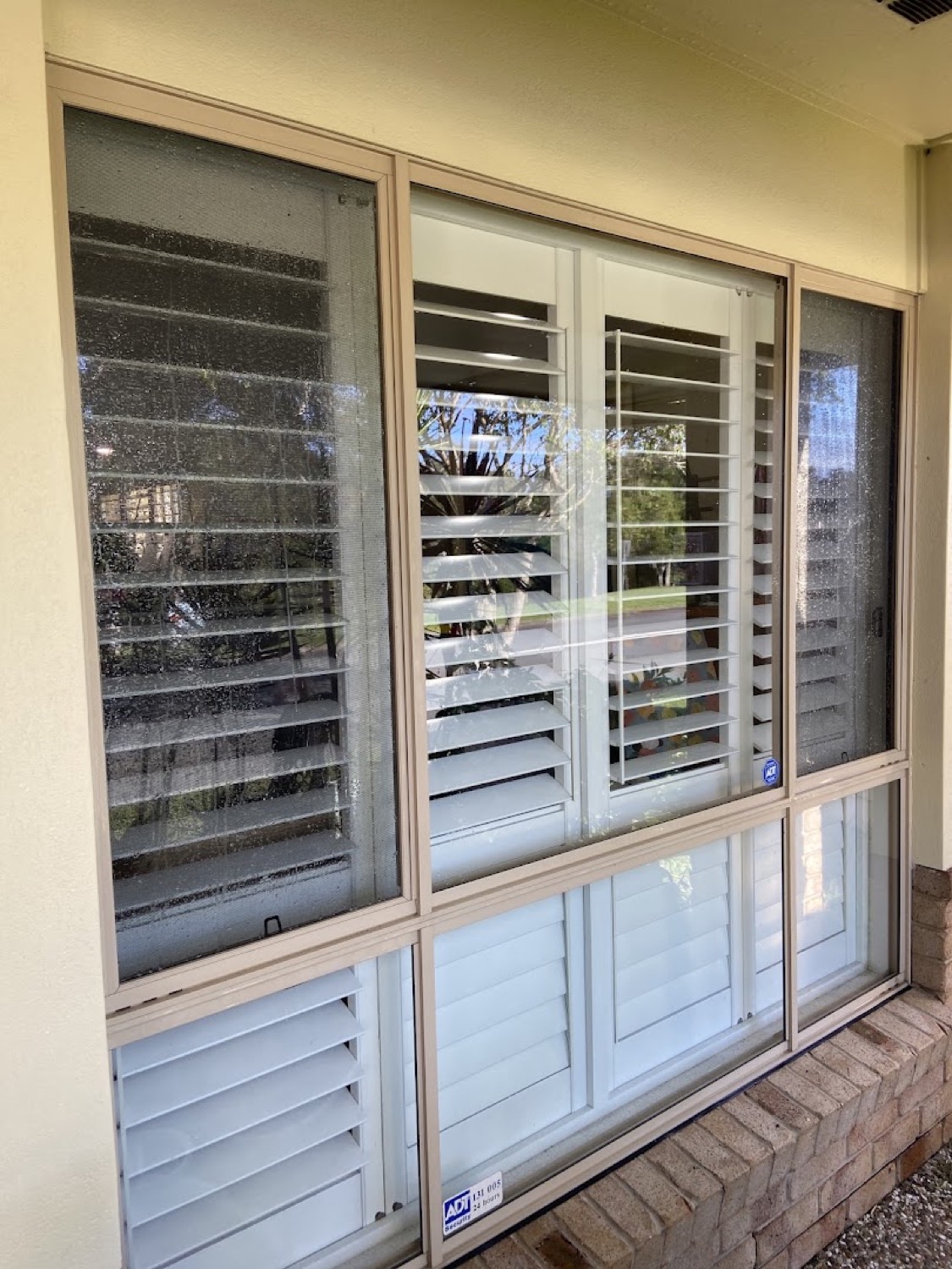 Cream-framed sliding windows with plantation shutters behind the glass